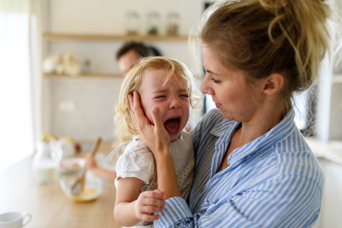 泣いている幼い女の子を抱っこする女性