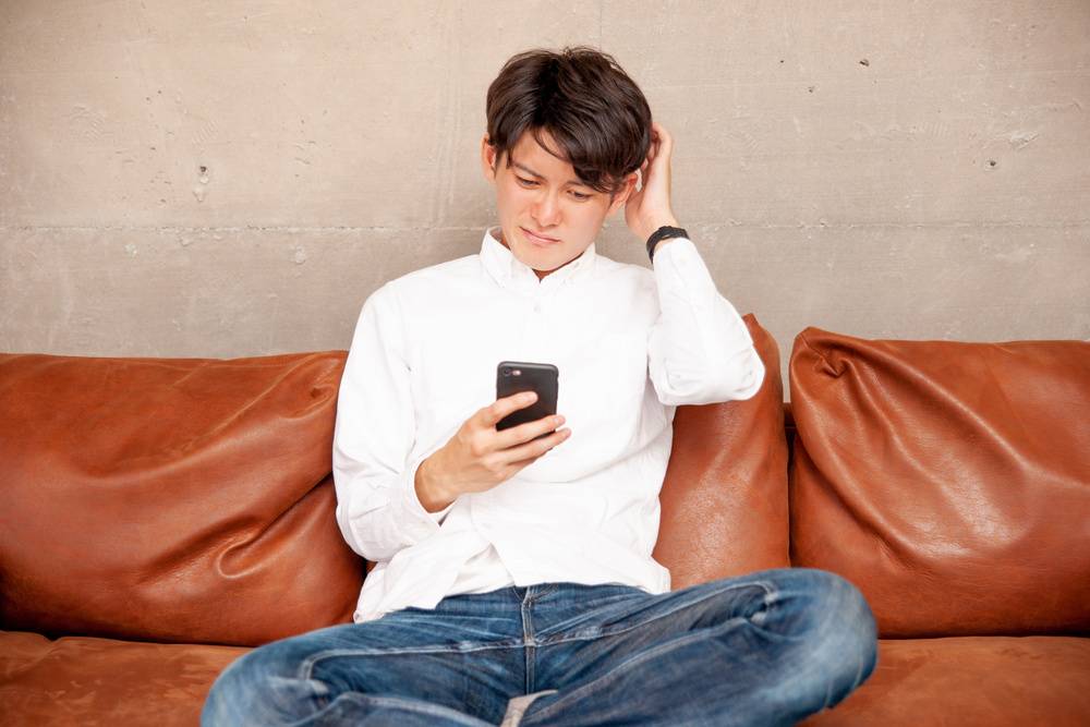 携帯を見て戸惑う男性