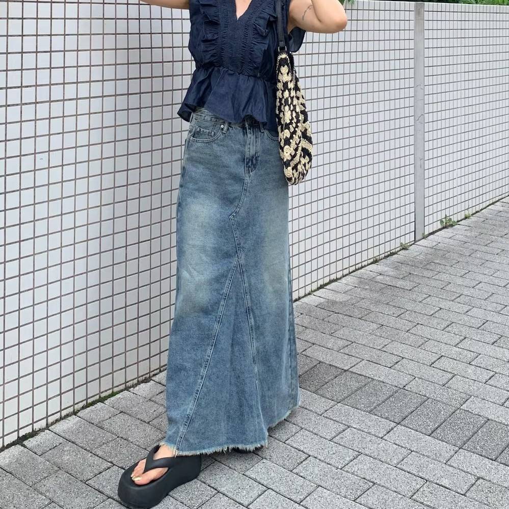 ブルーのブラウスにデニムスカートを合わせた女性