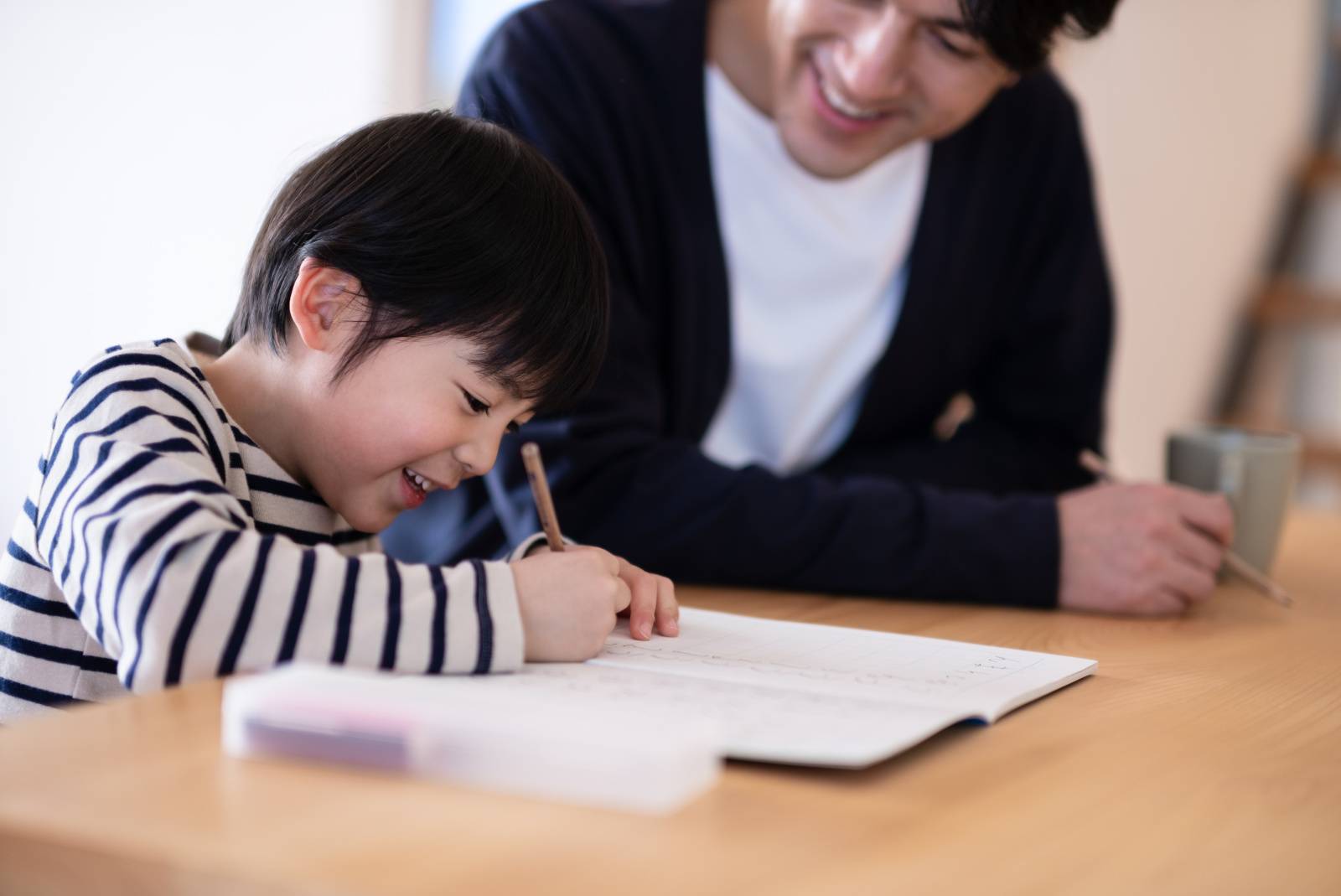 宿題をする男の子と見守る父親 