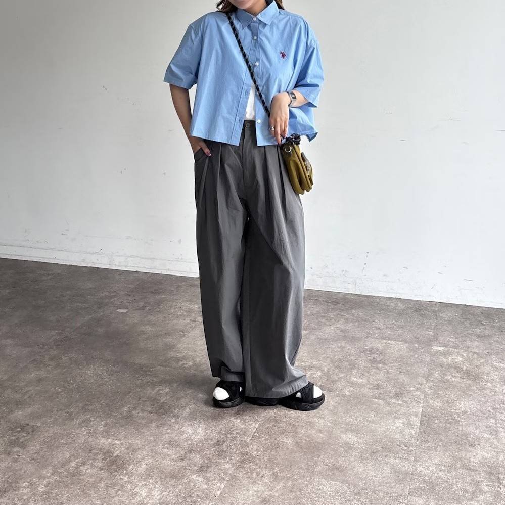 ブルーのシャツにグレーパンツを合わせた女性