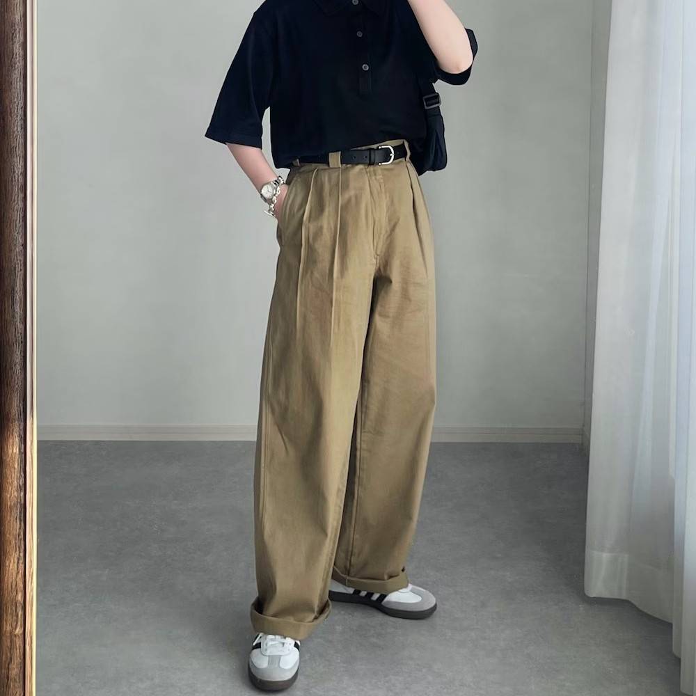 黒のポロシャツにベージュのパンツを合わせた女性