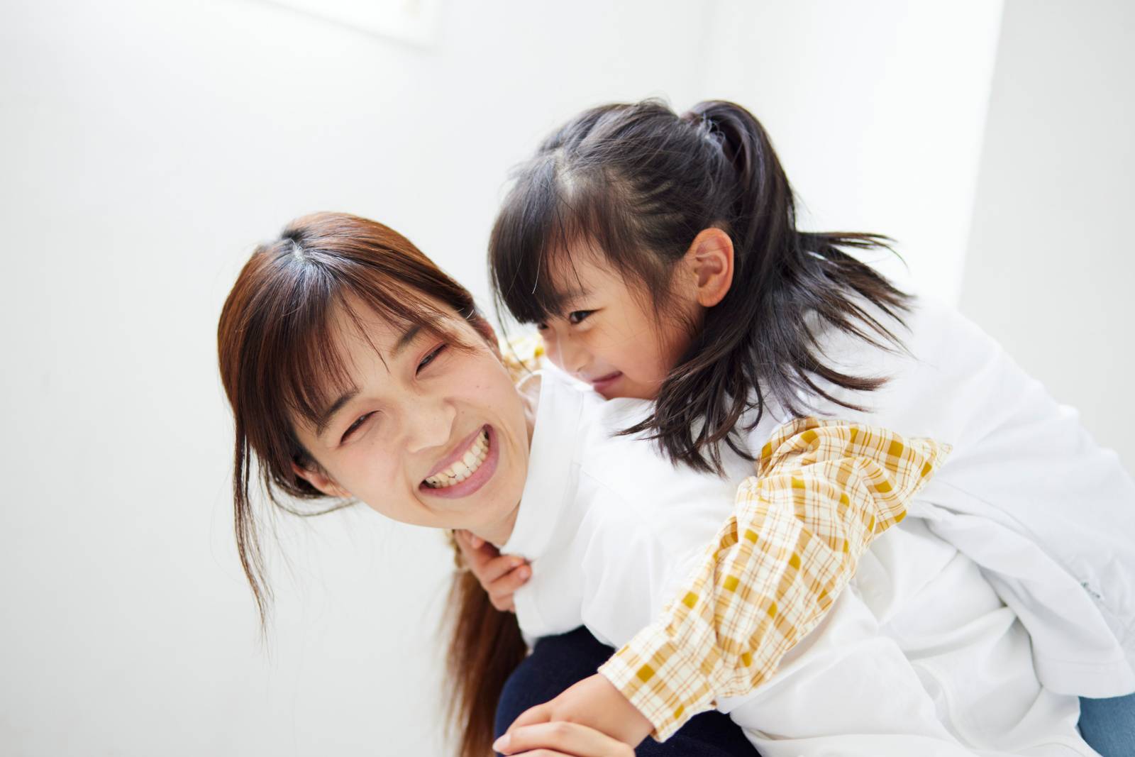 おんぶをして遊ぶ幸せそうな母親と子供 