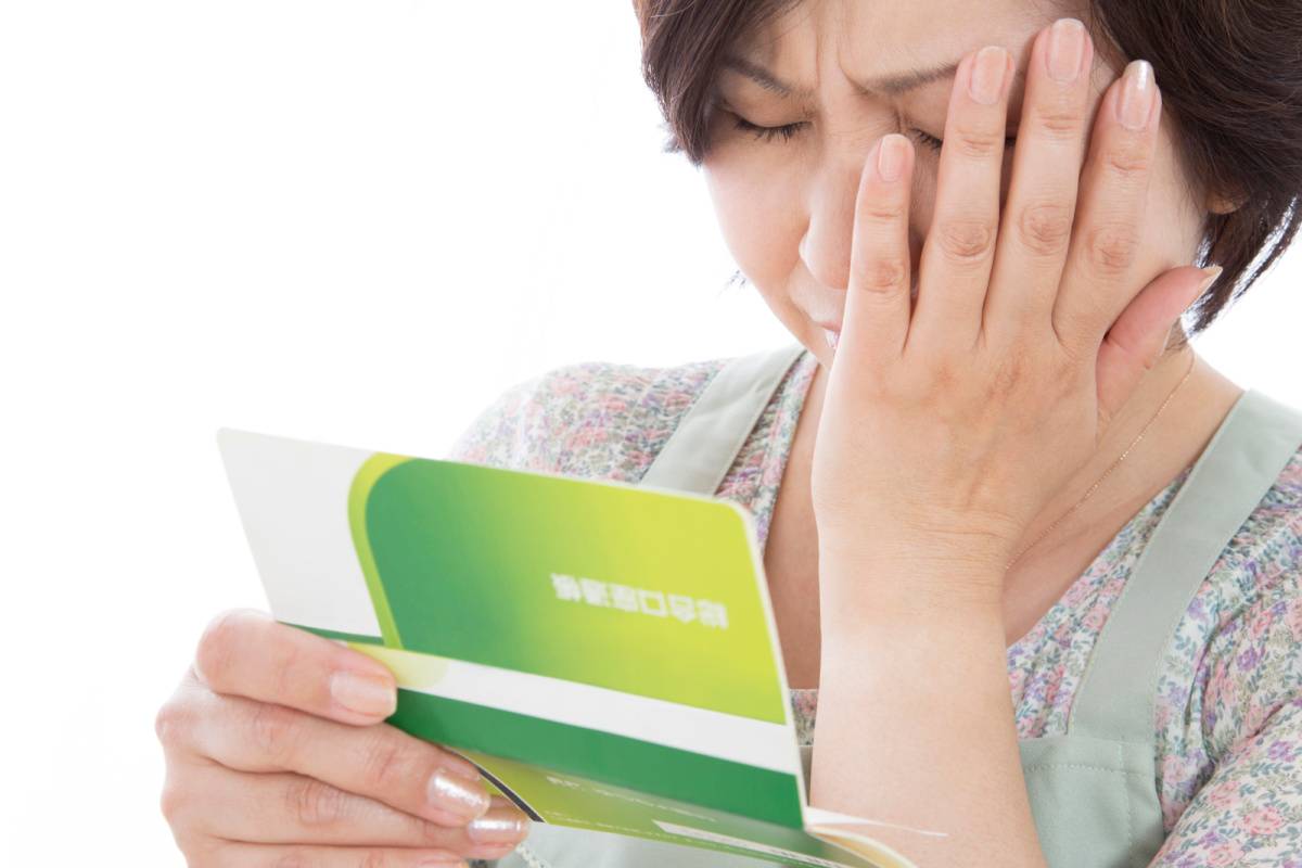 預金通帳を見る主婦 