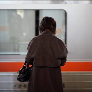  駅のホームで電車を待つ女性の後ろ姿 