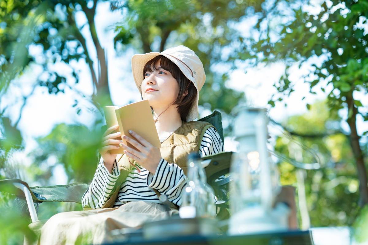 キャンプをしながら本を読む女性