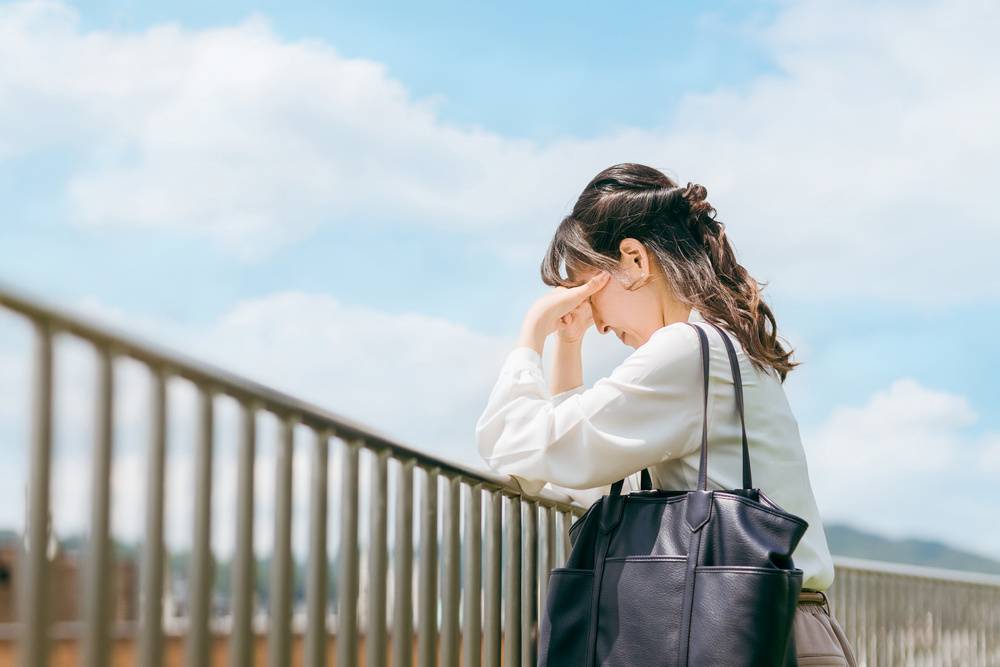 屋上で頭を抱える女性