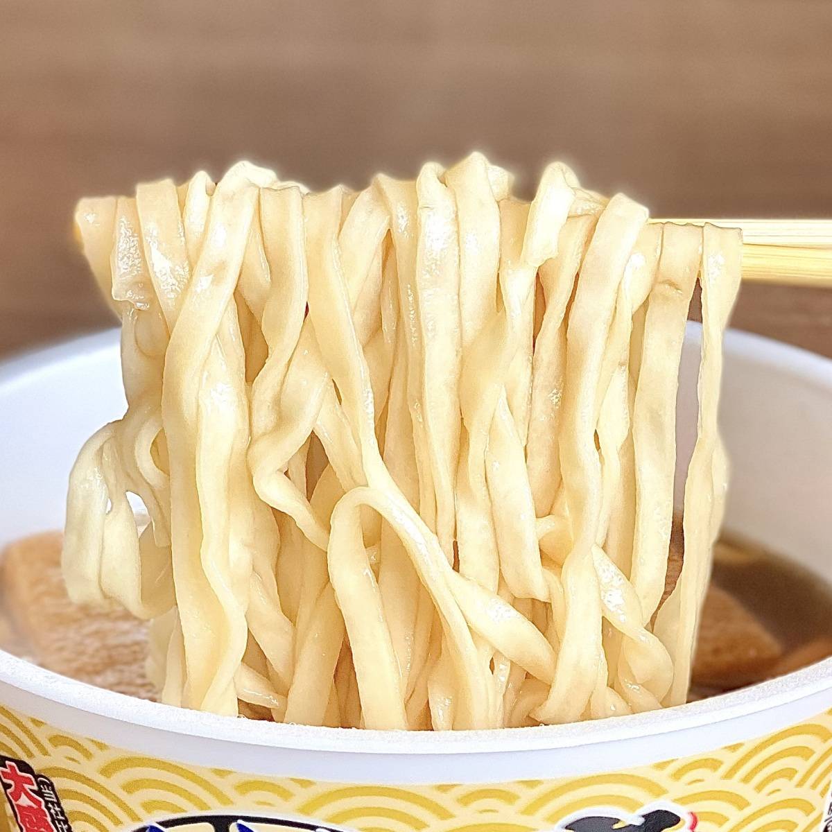 日清食品の「日清のニボどん兵衛 特盛 きつねうどん」の麺をお箸で掴む様子