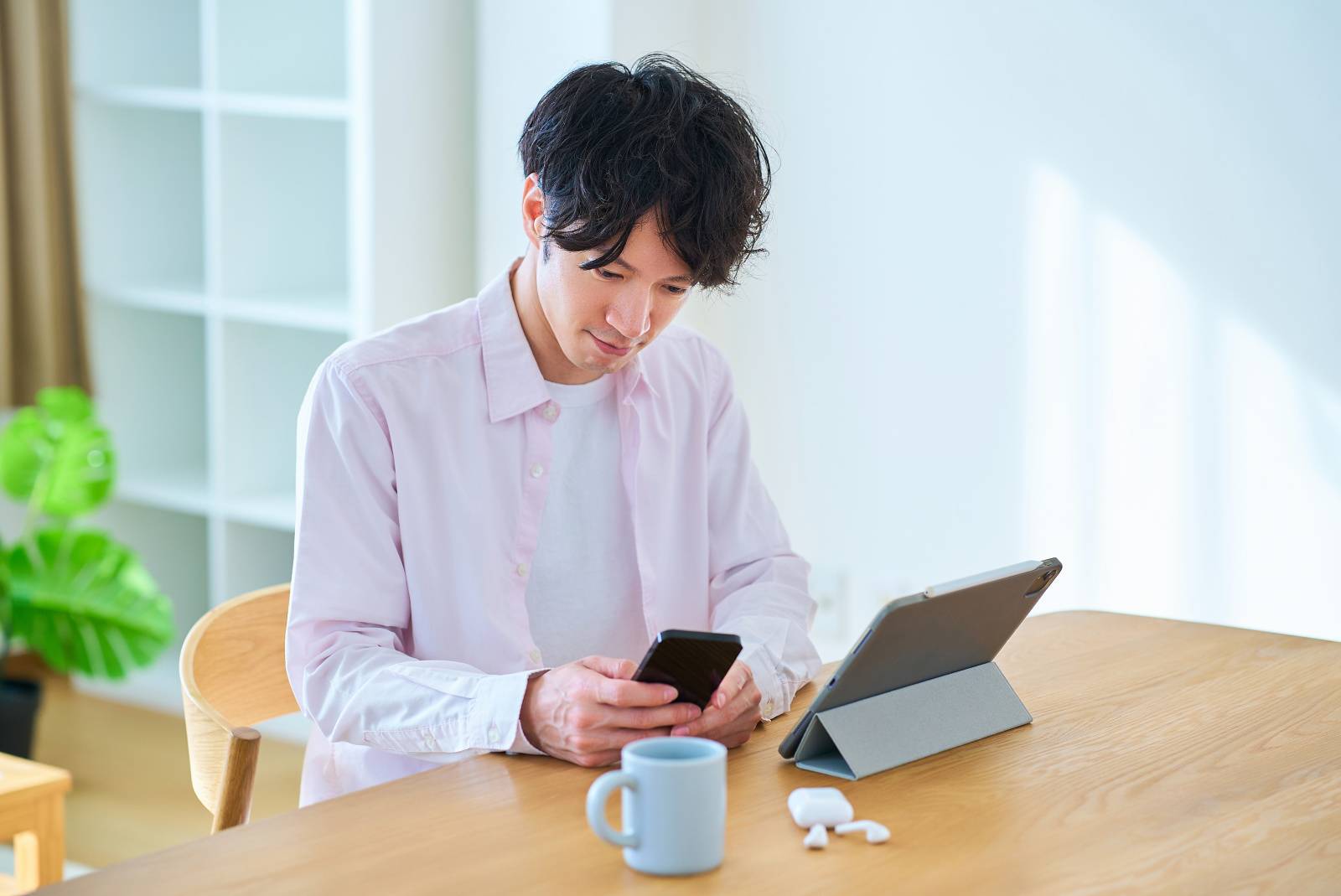 タブレットpcとスマートフォンを見比べる男性 