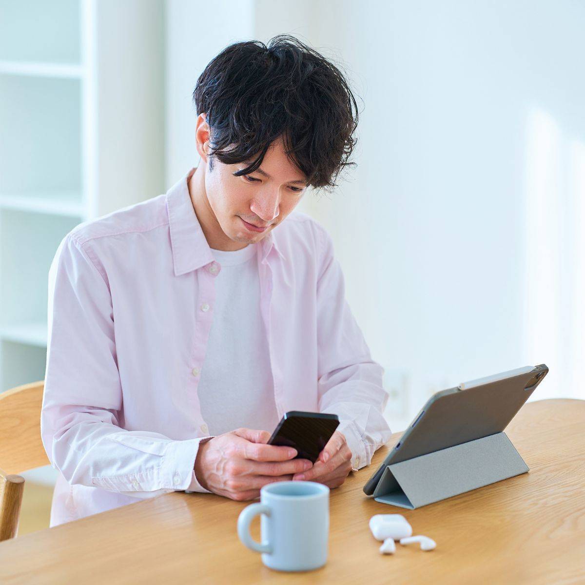 タブレットpcとスマートフォンを見比べる男性