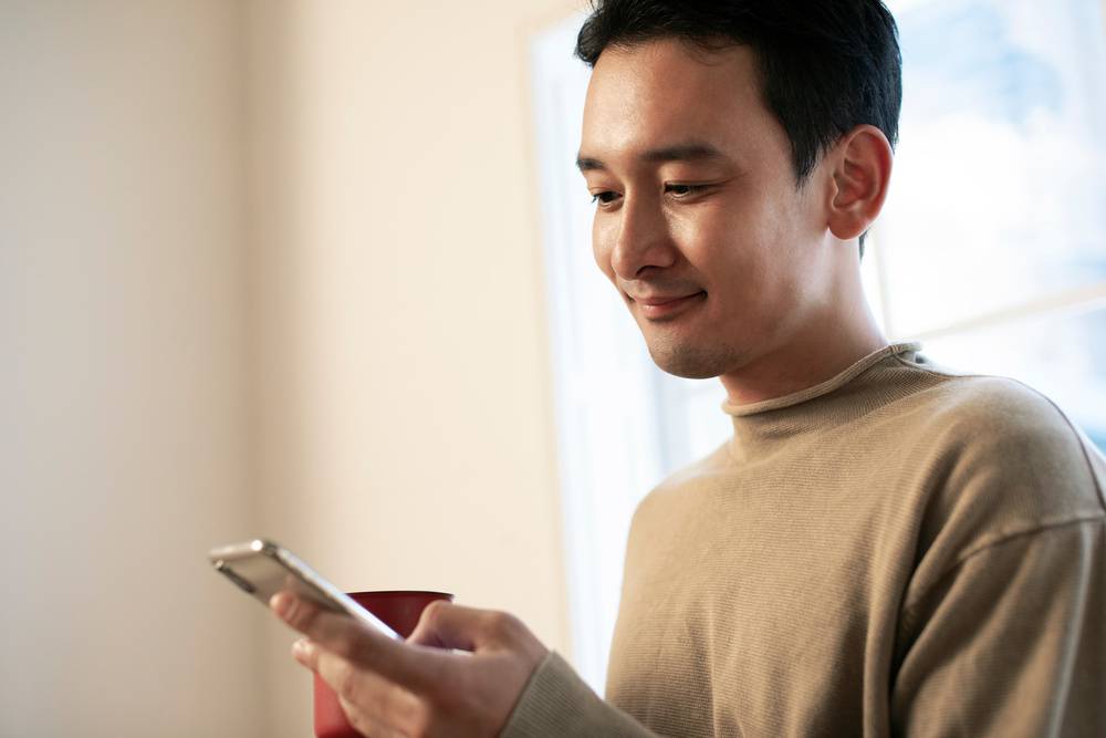 スマホ片手にニヤつく男性