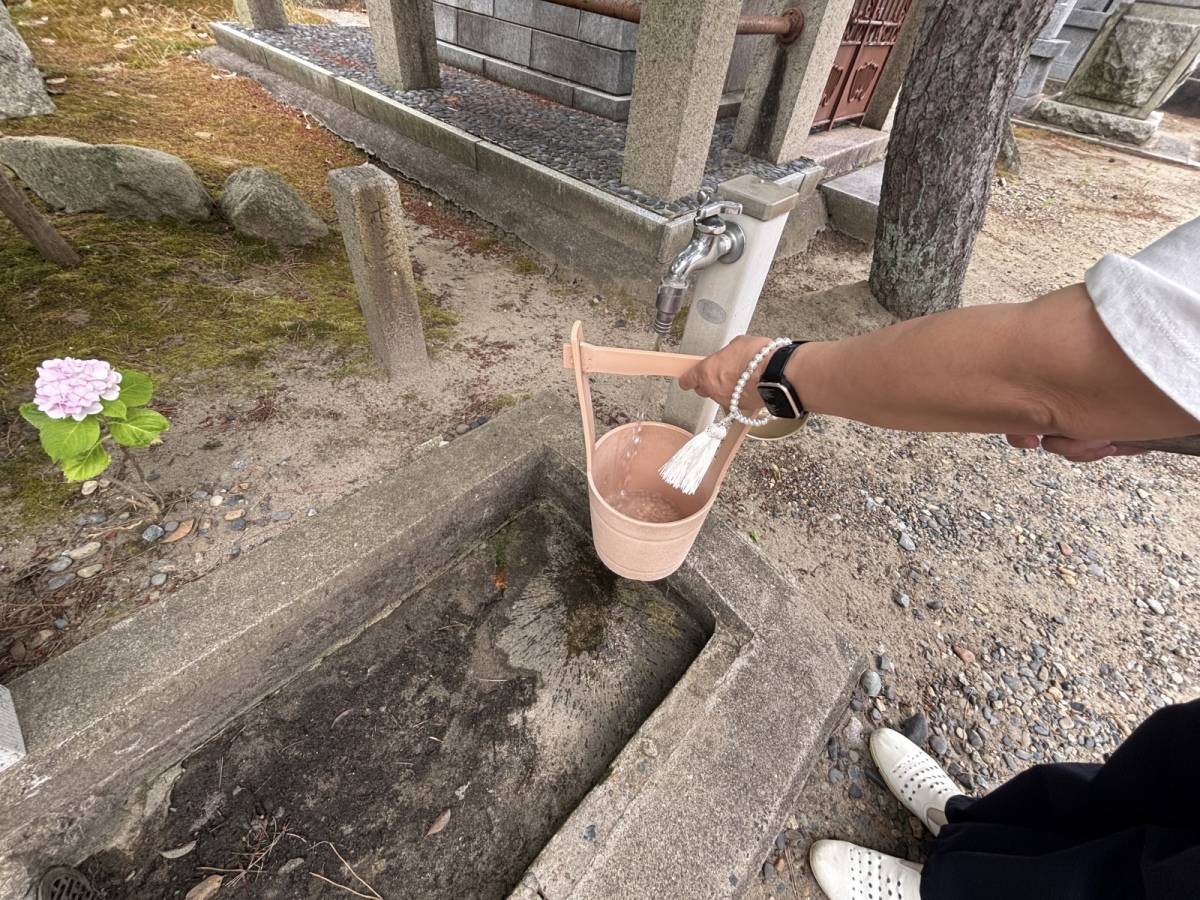 お墓を洗うための桶に水をいれている写真