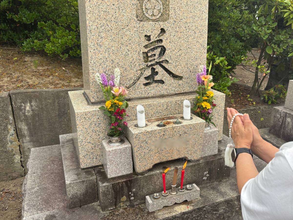 お墓の前で手を合わせる写真