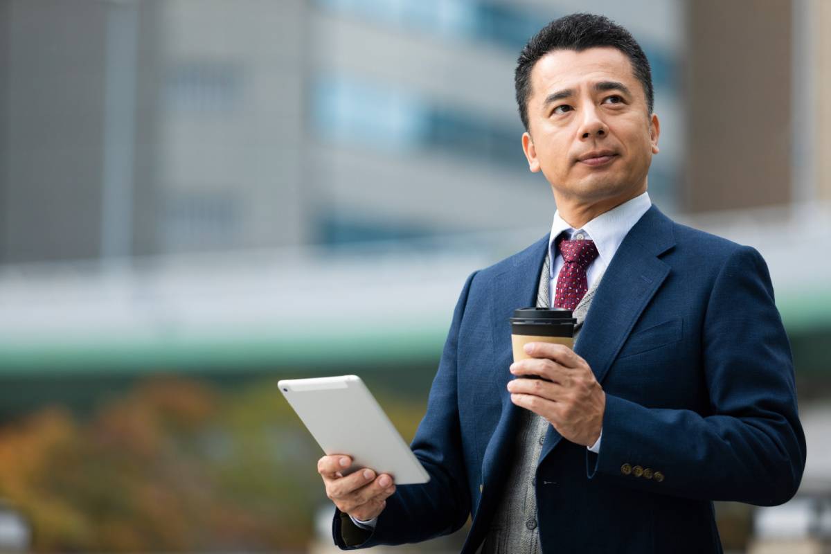 コーヒーとタブレットを持っている男性