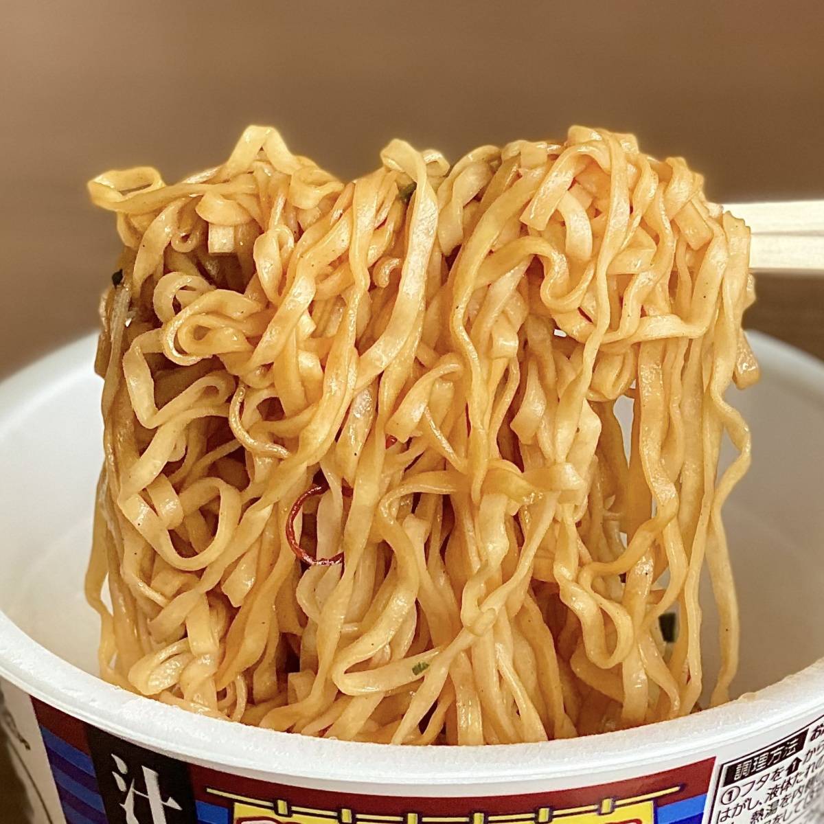 日清食品の「チキンラーメン汁なしどんぶり 焦がしにんにく香る油そば」の麺をお箸で掴む様子