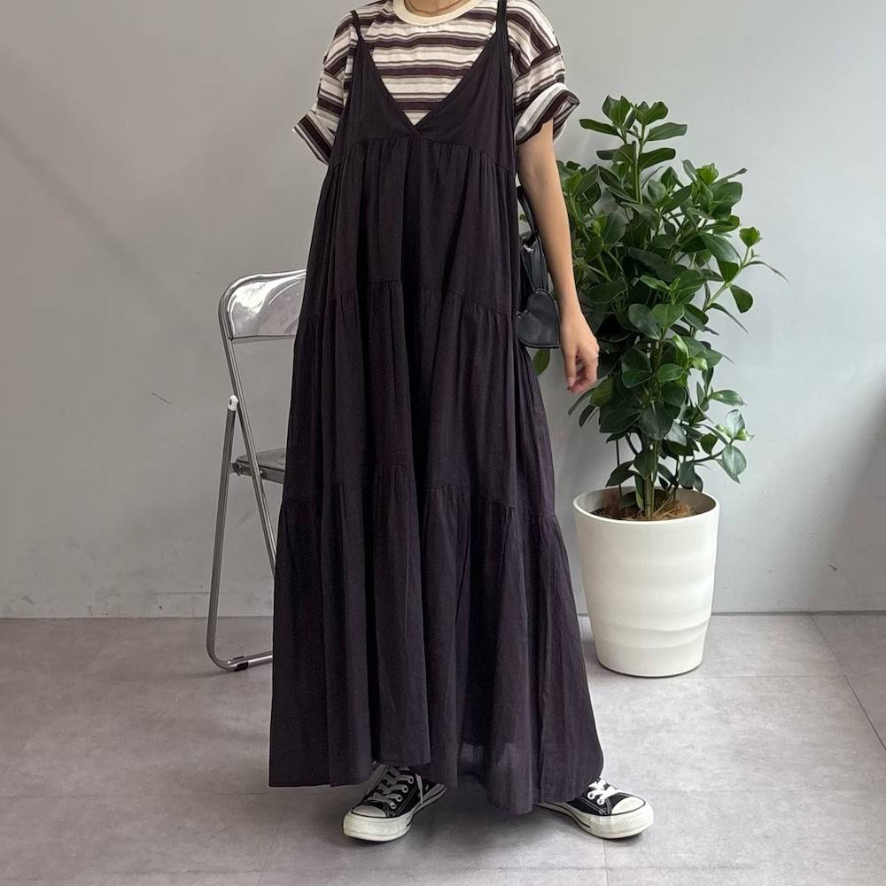 ボーダー柄のTシャツにブラウンのキャミワンピースを重ね着した女性