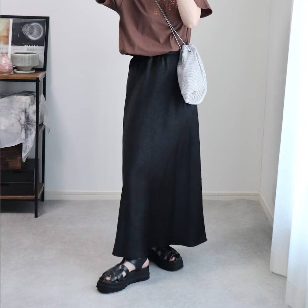 ブラウンのTシャツに黒スカートを合わせた女性