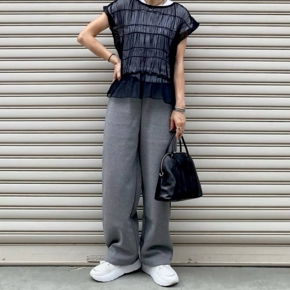 黒トップスにグレーパンツを合わせた女性