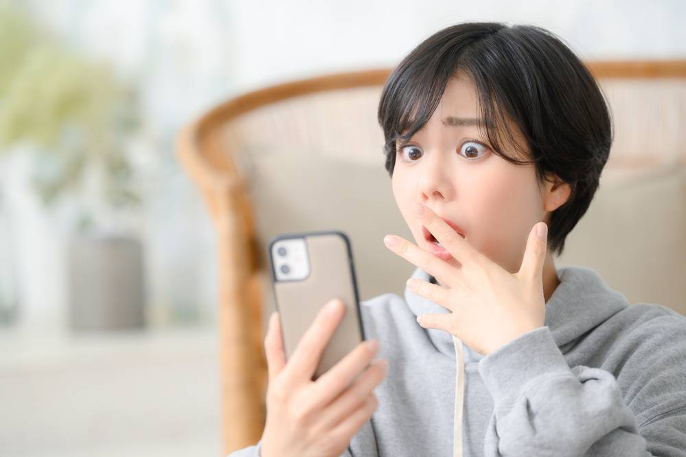 スマホを見て驚く女性