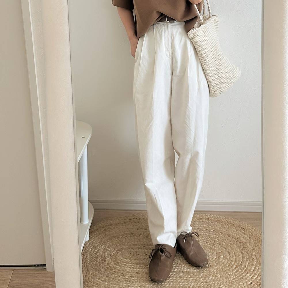 ブラウンのTシャツに白パンツを合わせた女性