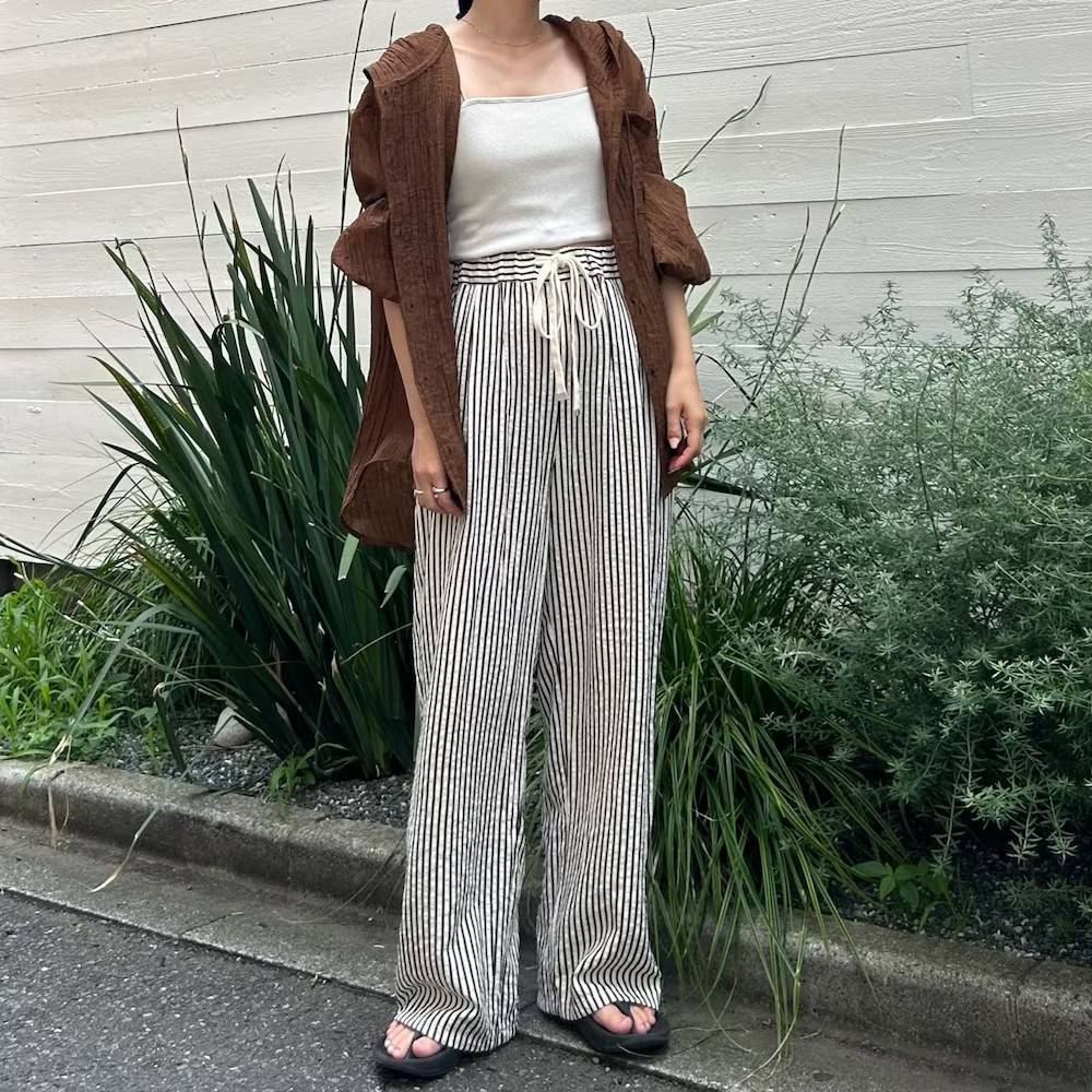 ブラウンのシャツにストライプ柄のパンツを合わせた女性