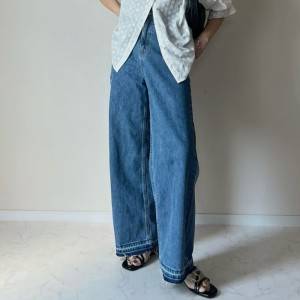  白ブラウスにデニムパンツを合わせた女性 