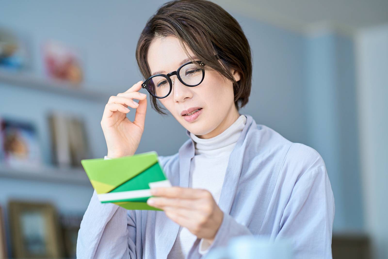 困った表情で銀行口座の通帳を見る女性