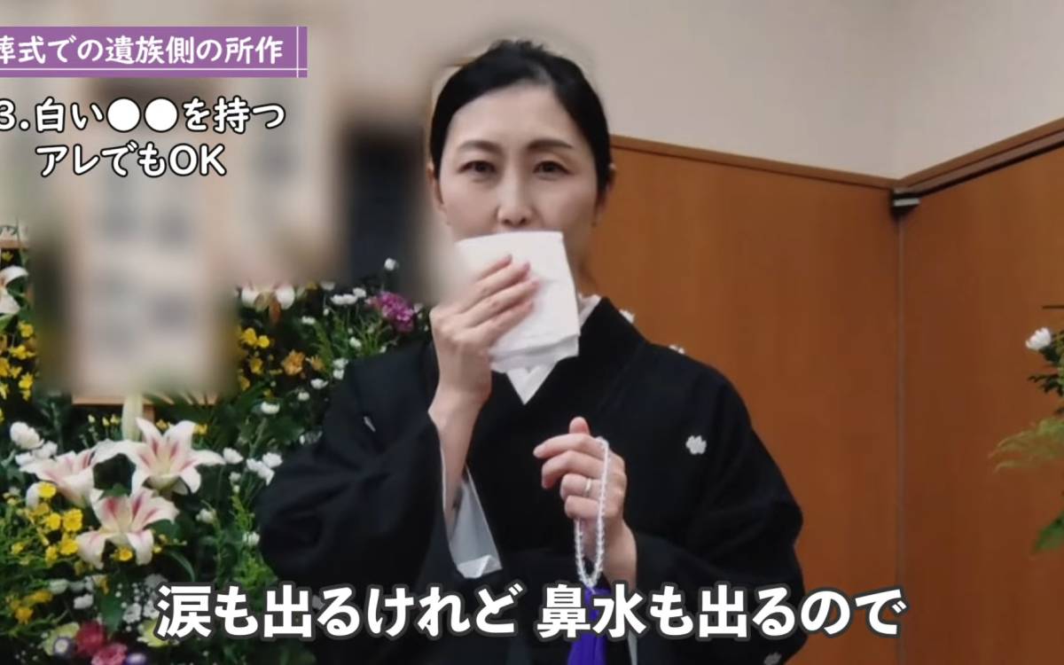 白いハンカチを顔にあてる女性