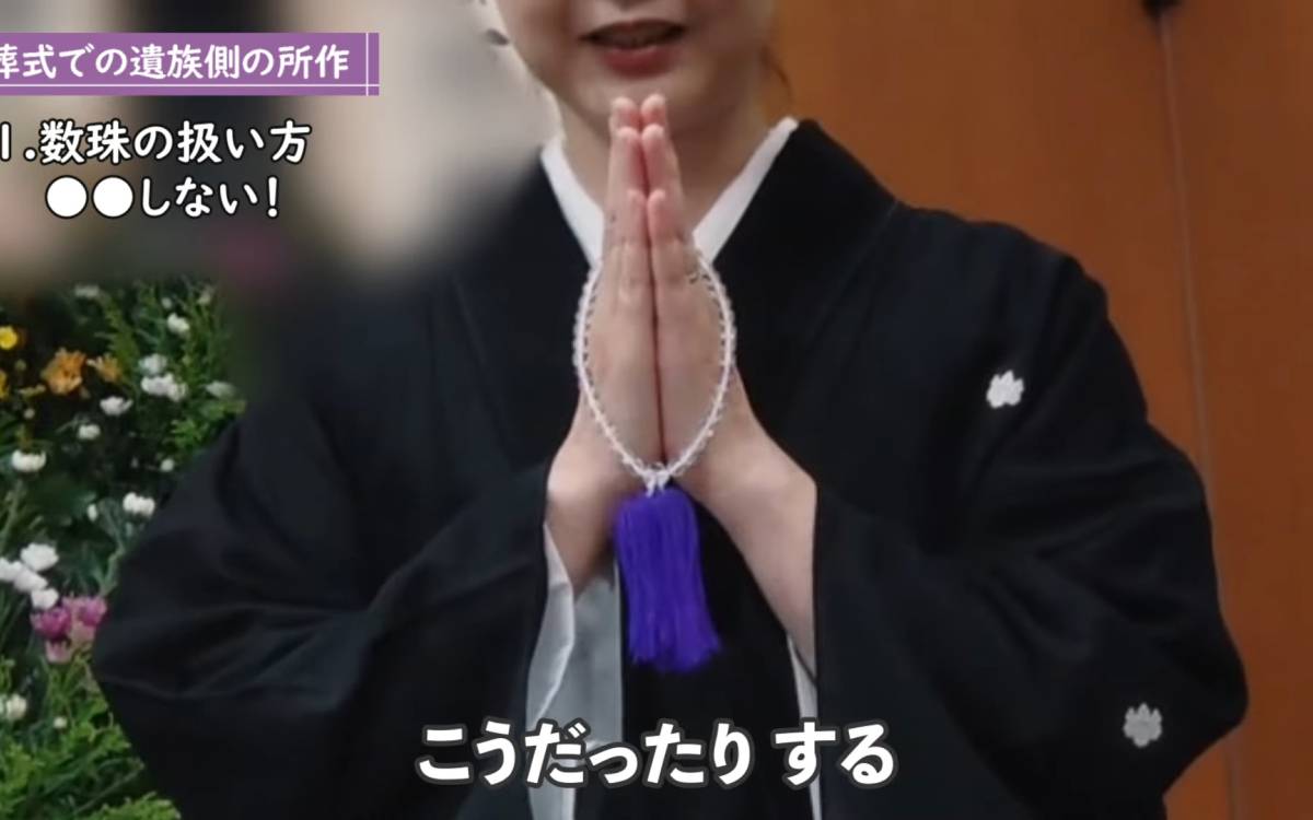 数珠を持って手を合わせる女性