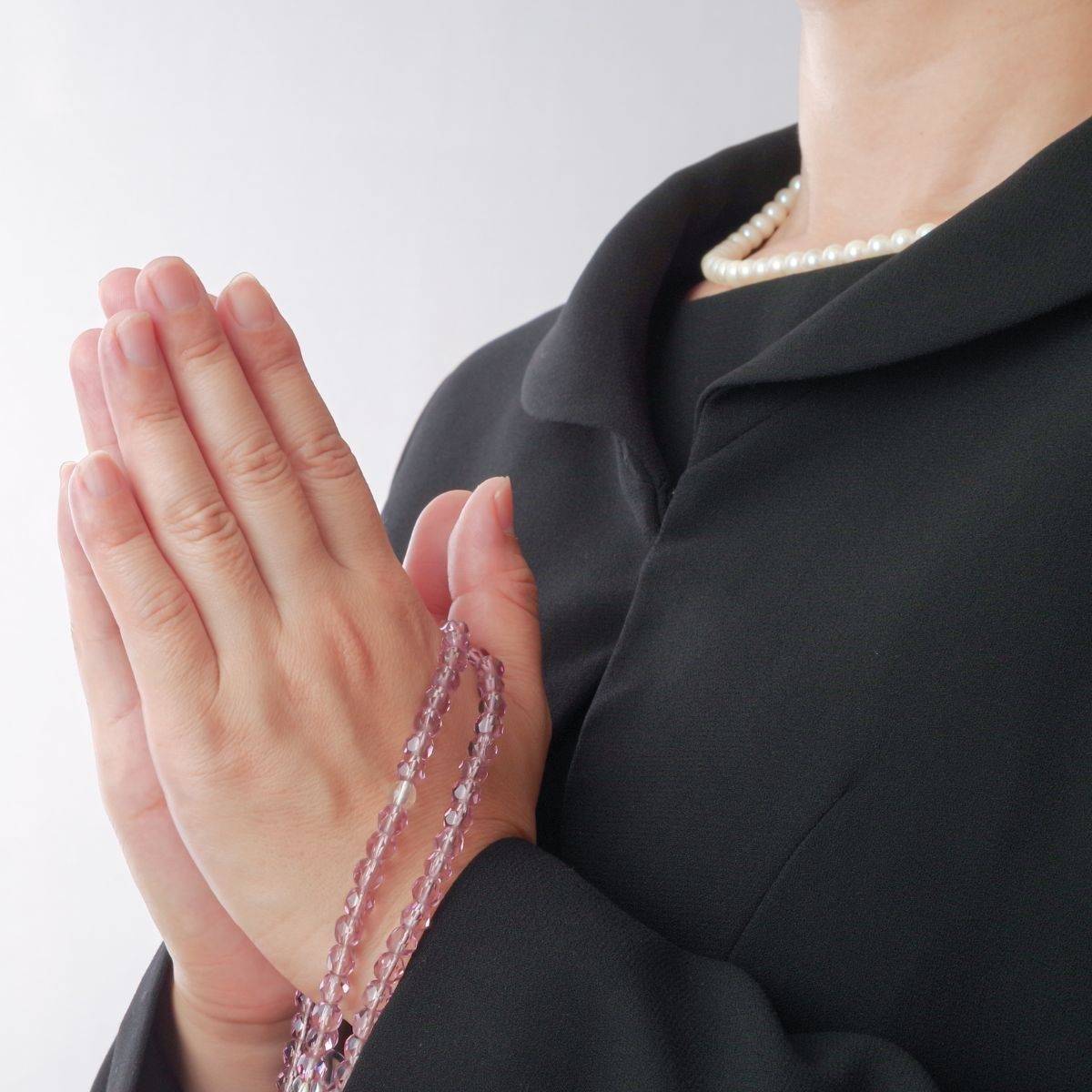 数珠を持って手を合わせる女性