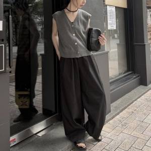  グレーのトップスに黒パンツを合わせた女性 