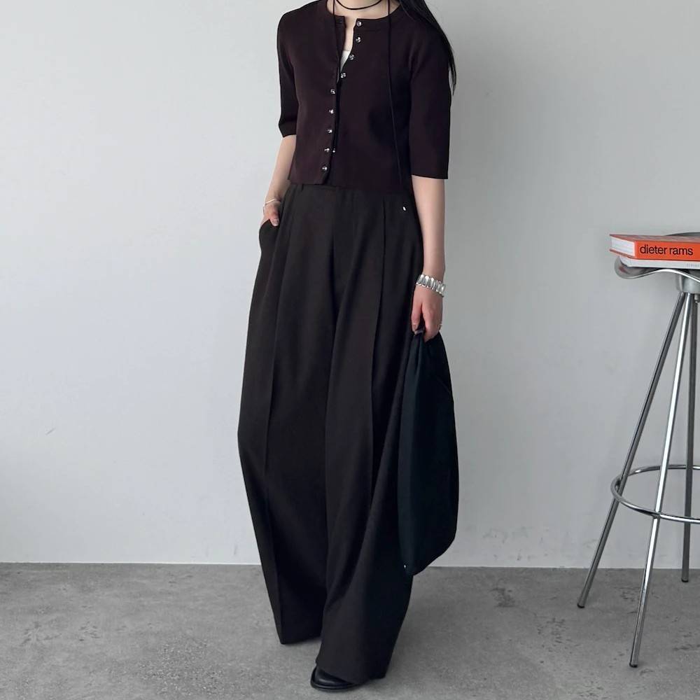 ブラウンのトップスに黒パンツを合わせた女性