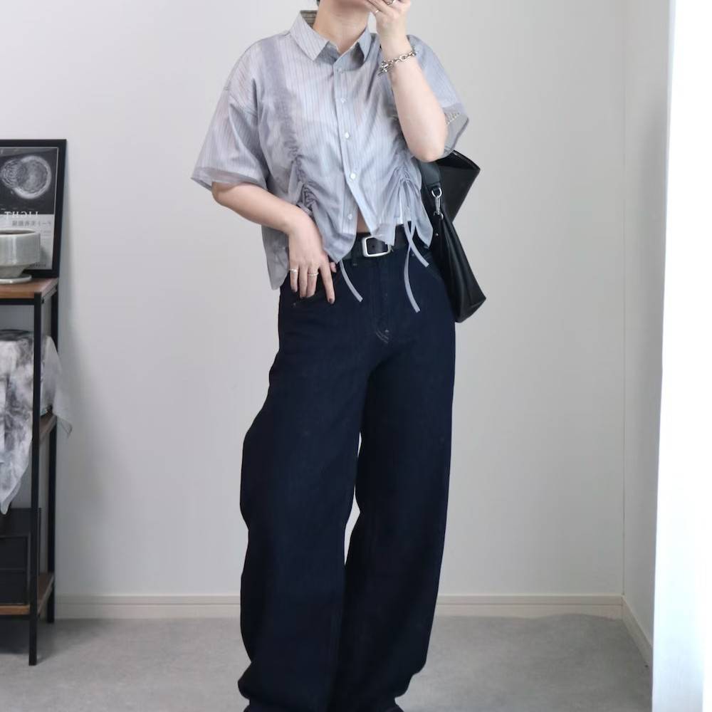 ストライプ柄のシャツにデニムパンツを合わせた女性