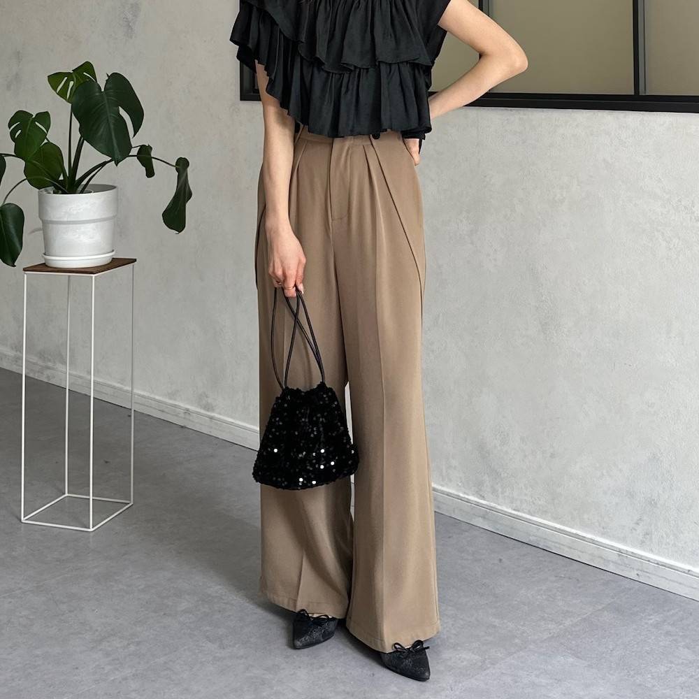 黒トップスにベージュにパンツを合わせた女性