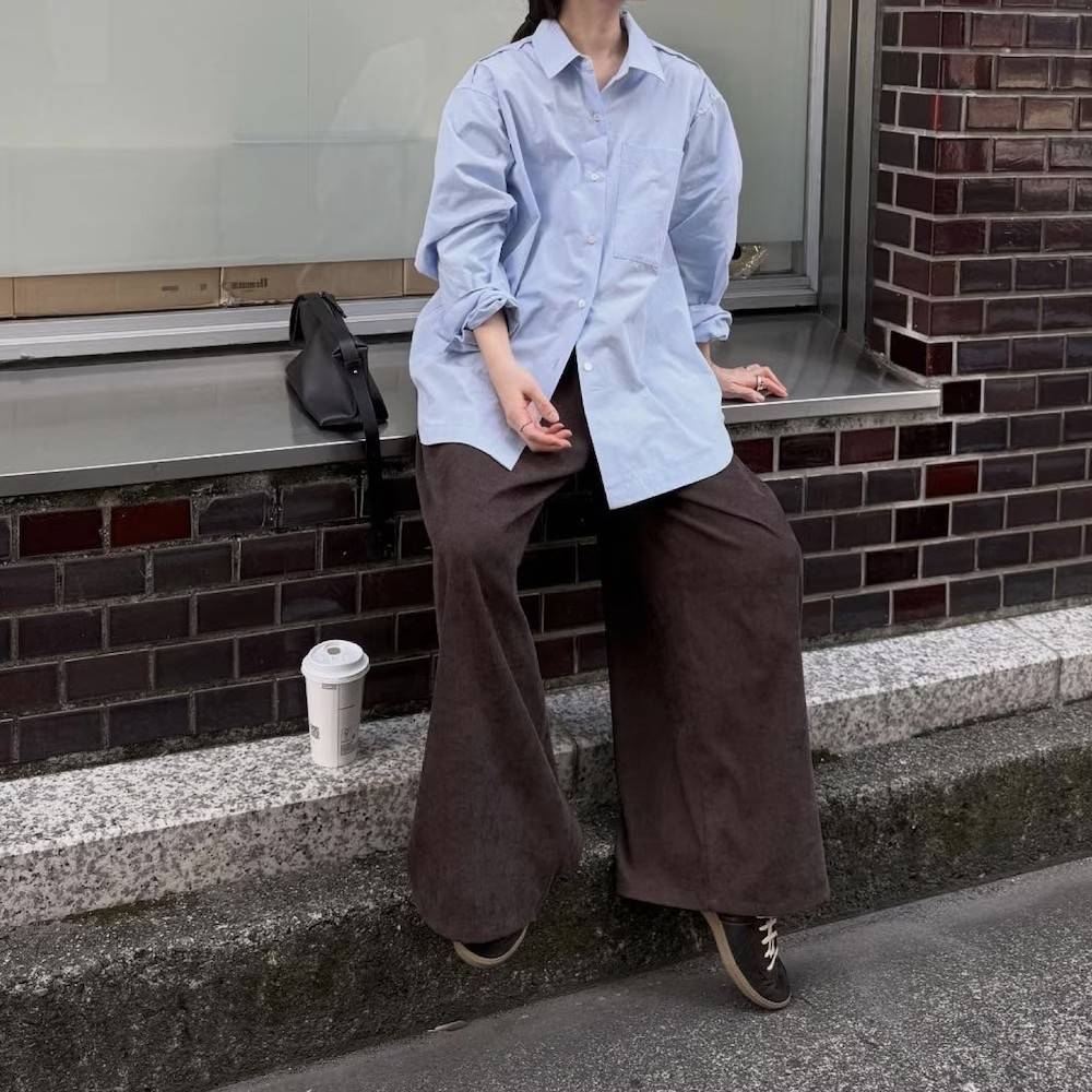 ブルーのシャツにブラウンのパンツを合わせた女性