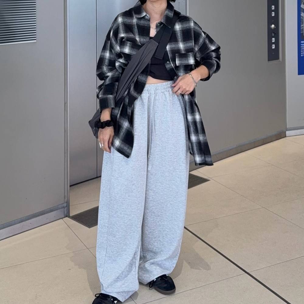 チェック柄のシャツにグレーのパンツを合わせた女性
