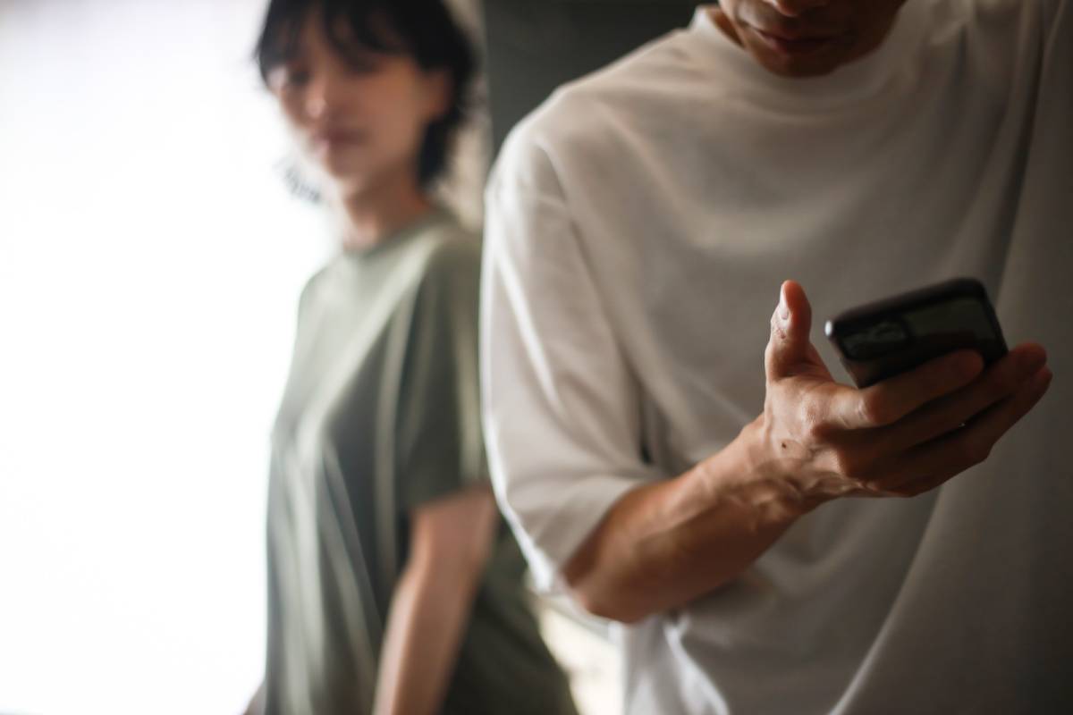 女性に隠れてスマホを見ている男性