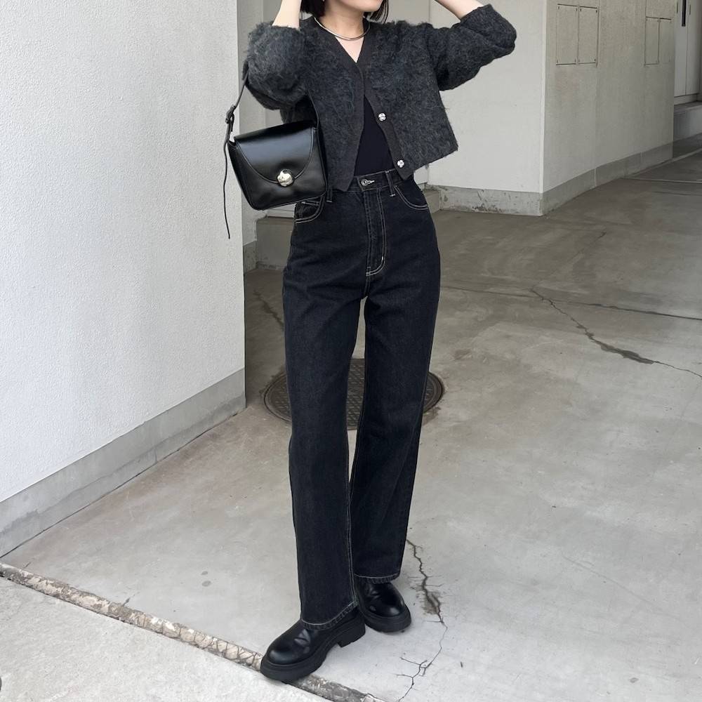 グレーのカーディガンにデニムパンツを合わせた女性