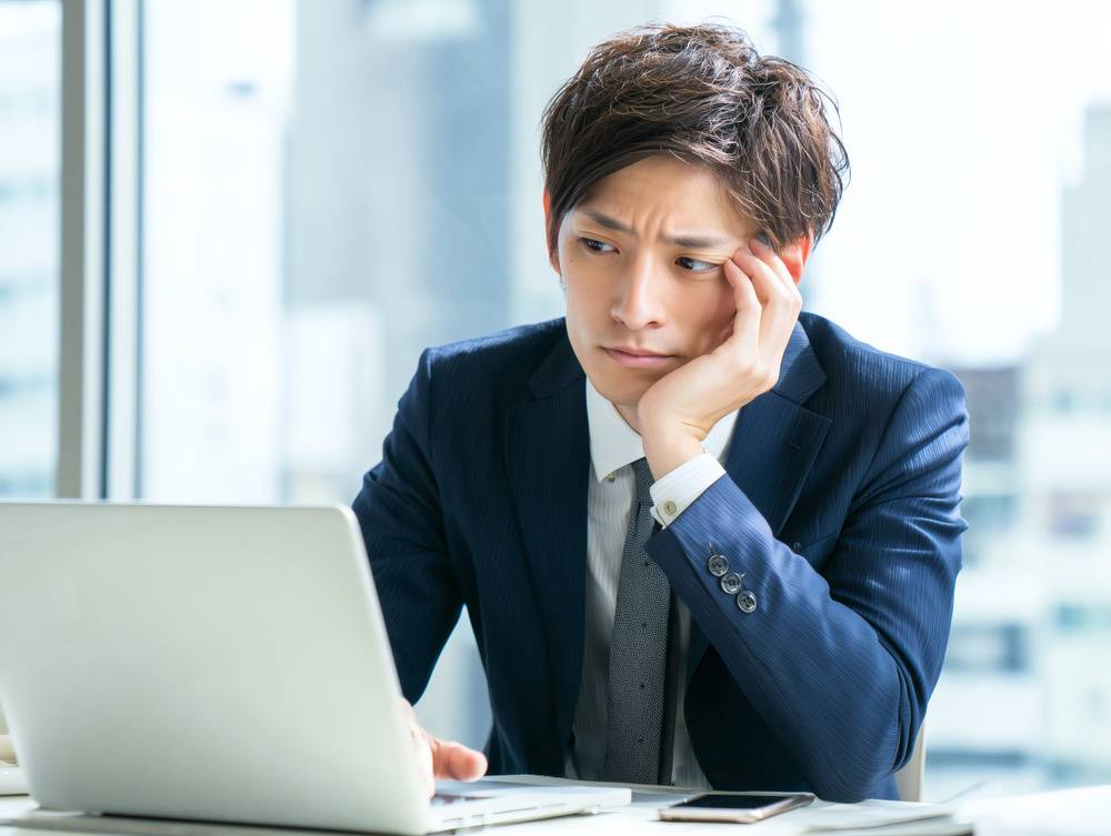 PCの前で悩む男性