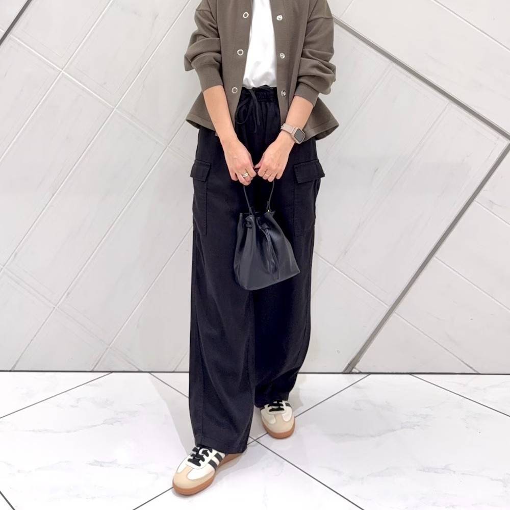 ブラウンのカーディガンに黒パンツを合わせた女性