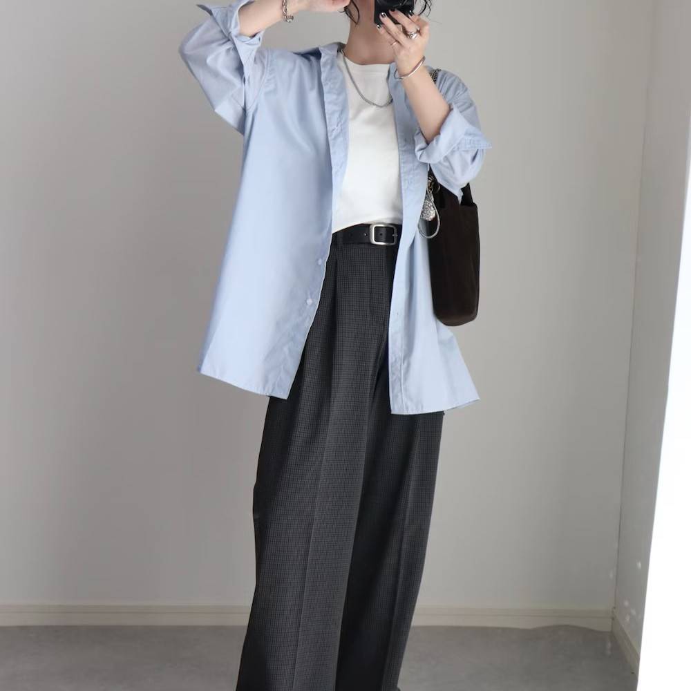 ブルーのシャツにグレーのパンツを合わせた女性