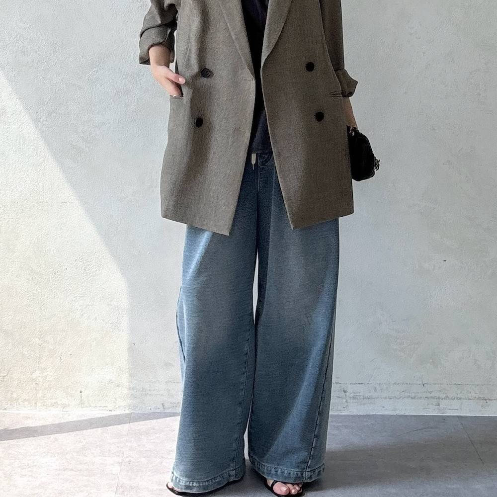 ブラウンのジャケットにデニムパンツを合わせた女性