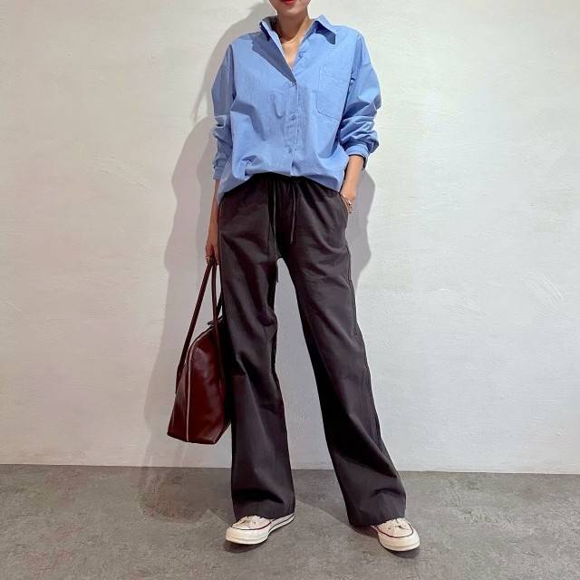 ブルーのシャツにグレーパンツを合わせた女性