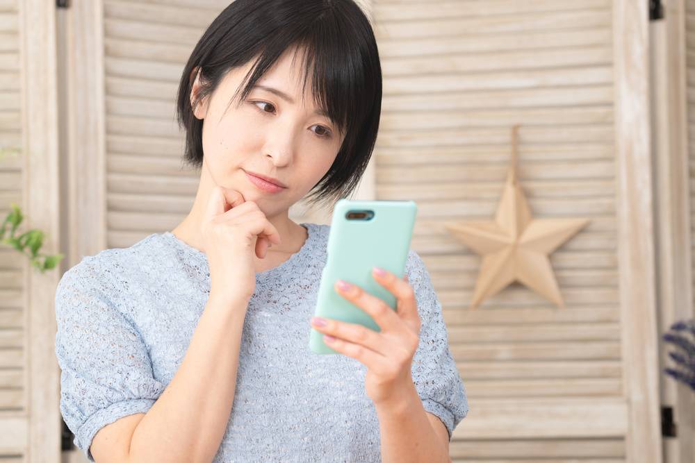 スマホを見て困惑する女性