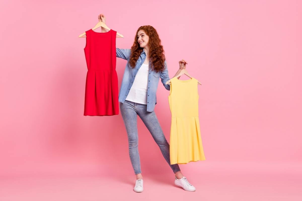 両手に違う色のワンピースを手にする女性