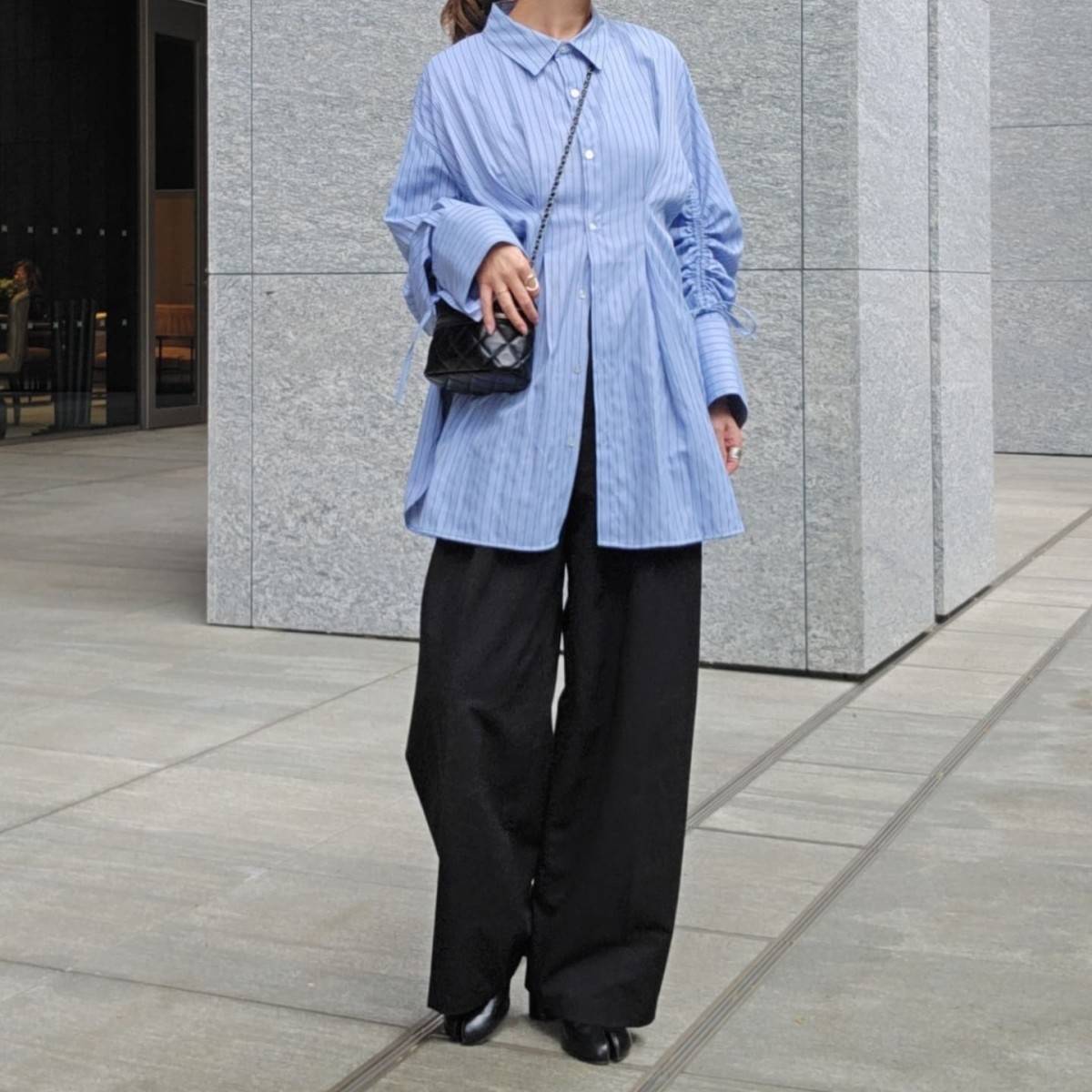 ブルーのシャツに黒パンツを合わせた女性