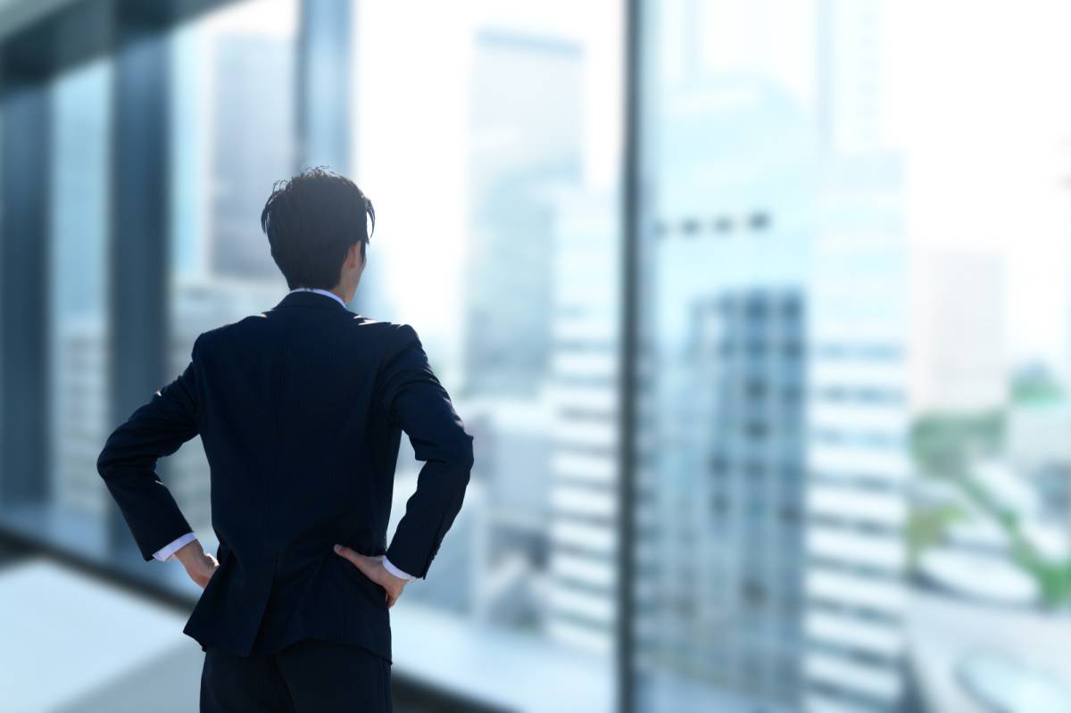 窓を見つめるスーツ姿の男性