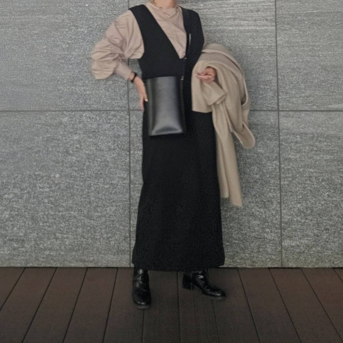 ベージュのブラウスに黒ワンピースを重ね着した女性