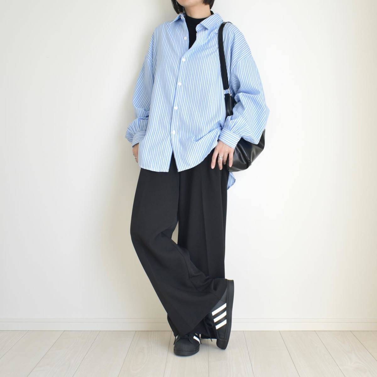 ブルーのシャツに黒パンツを合わせた女性