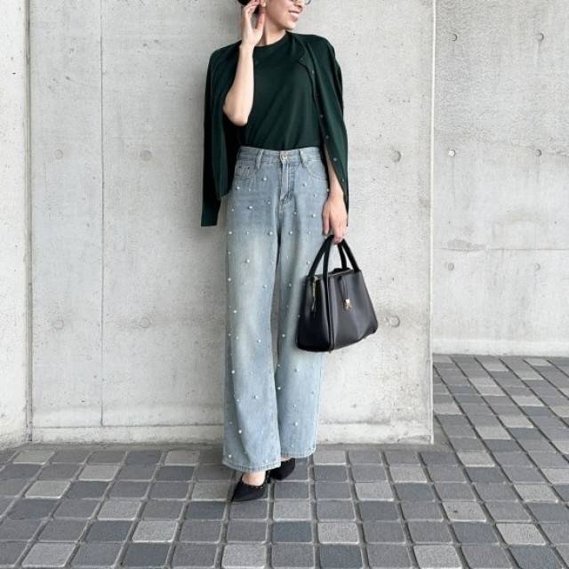 グリーンのトップスにデニムパンツを合わせた女性